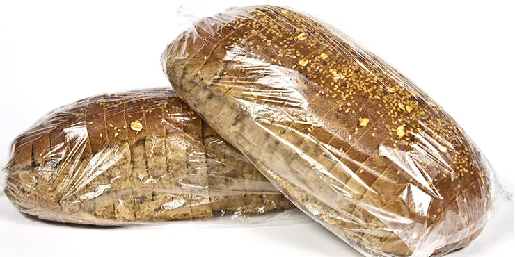 Top view of two baguettes baked bread in paper with different seeds (pumpkin, poppy, flax, sunflower, sesame, millet) decorated with ears of wheat isolated on white background.