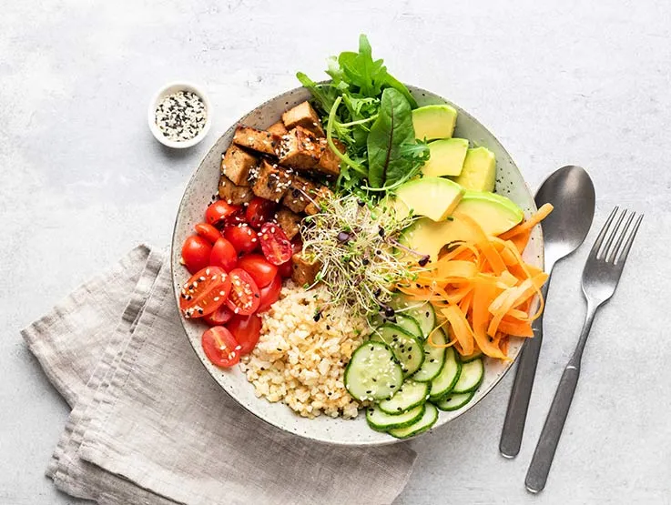 A bowl with fresh vegetables, healthy fats and whole grains