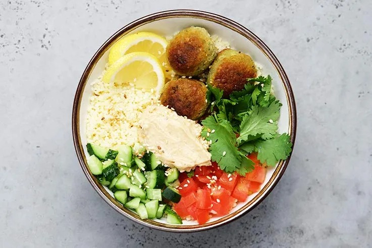 A bowl with falafels and fresh salad ingredients 