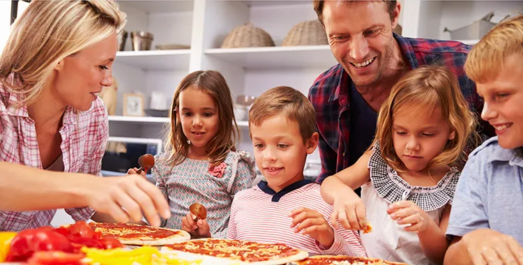 Mum, Dad and four kids, two sons and two daughters, in kitchen making pizza from scratch