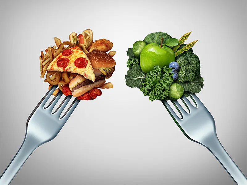This image shows two forks. On the left fork, sits a pile of fatty junk food - generally considered to be bad for our health. On the right fork sits all the green vegetables and fruits - generally considered to be good for us.