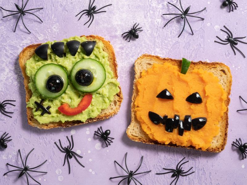 Creative monster-themed Halloween toasts with vegetables, featuring Frankenstein and Jack-o-lantern designs.