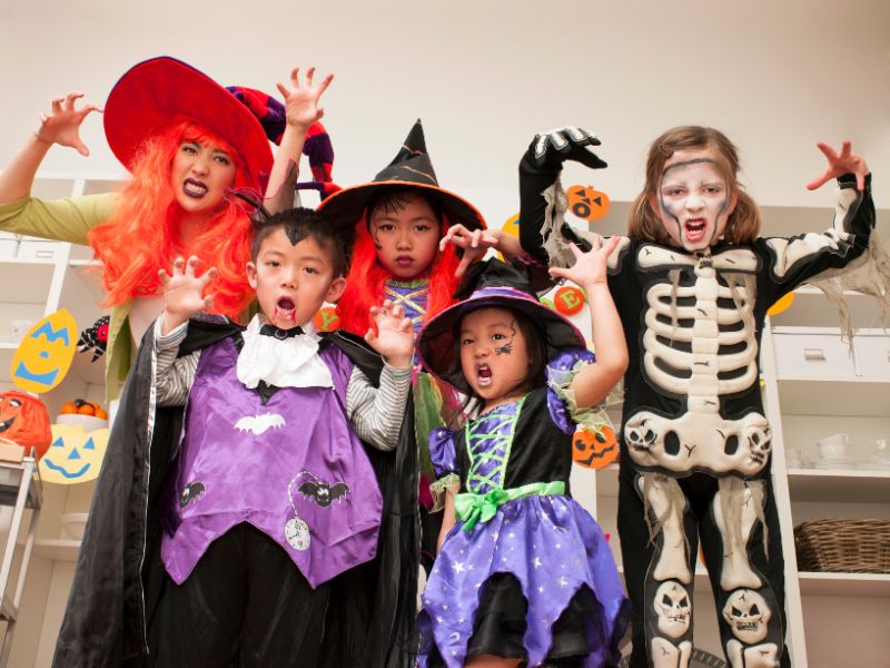 Group of kids dressed in Halloween costumes posing indoors for a fun and healthy holiday celebration.