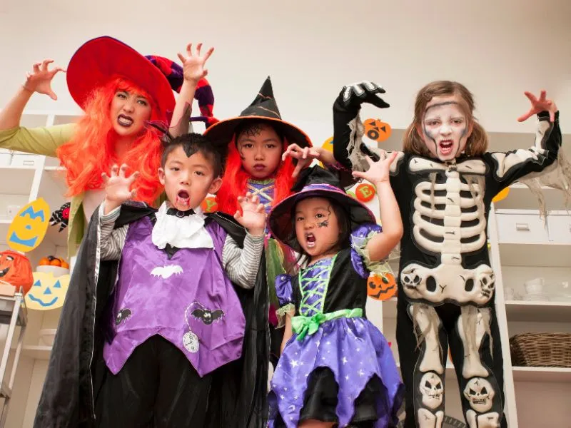 Group of kids dressed in Halloween costumes posing indoors for a fun and healthy holiday celebration.