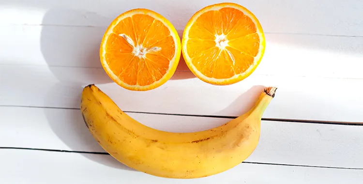 Healthy food for good mental health. Two half oranges and a banana that look like eyes and a smile for a happy face