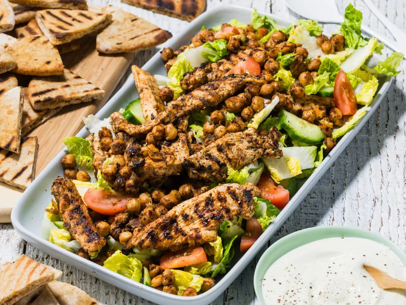 Colourful chicken and vegetable kebabs with capsicum, zucchini and onion grilling on a hot barbecue, heart healthy summer BBQ skewers, fresh grilled vegetable kebab close up.