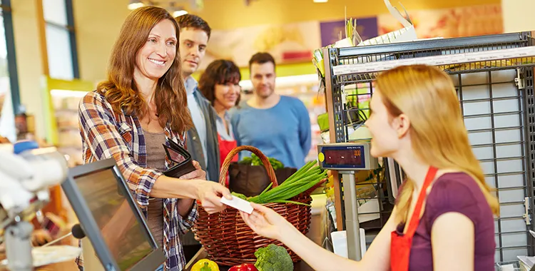 Woman shopping at supermarket, paying at checkout