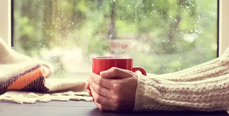 Woman holding warm drink on a rainy day