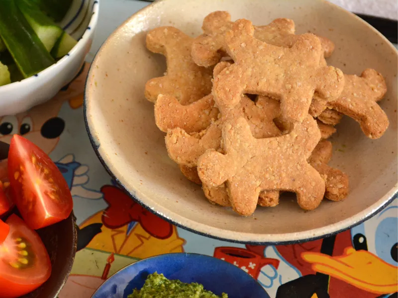Crunchy almond and oat crackers on a platter alongside fresh vegetables and green dip.
