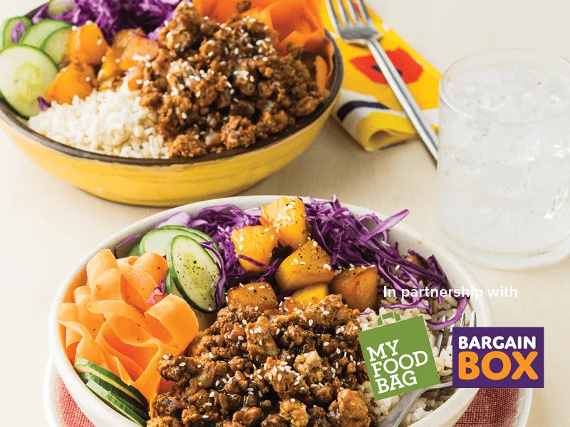 Bowls of pork with grilled pineapple and brown rice on a white table