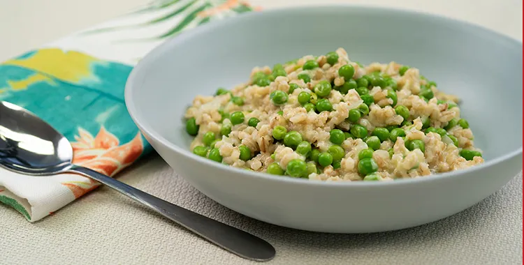 Barley and pea “orzotto” — a creamy pearl barley risotto studded with green peas, served in a shallow gray bowl.