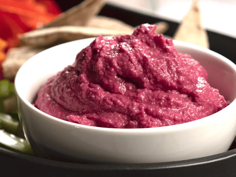 Beetroot hummus—creamy, vibrant dip made from roasted beetroot, chickpeas, tahini, lemon, garlic, and cumin—served in a white bowl, perfect with pita or veggies.