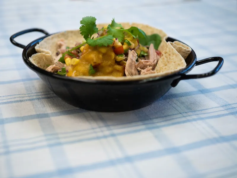 Braised pork wrap with salsa and coriander served in a black pan.