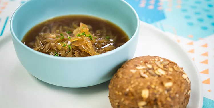 Caramelised onion soup in a bowl with a bread roll