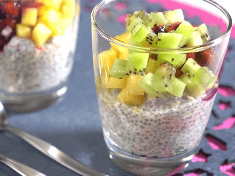 Chia and oat pudding layered in glasses and topped with diced kiwi and mango for a fresh, make‑ahead breakfast.