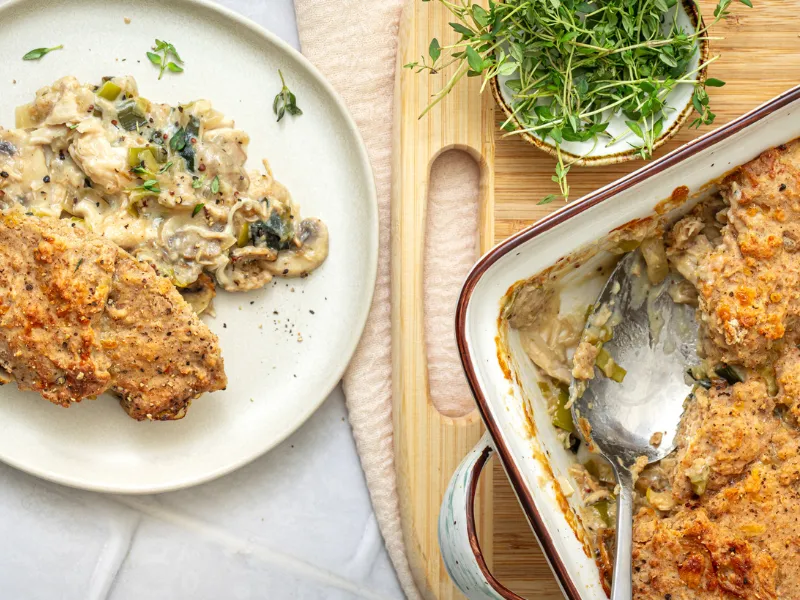 Creamy chicken and mushroom casserole served with a golden breadcrumb topping and fresh thyme on a light plate and wooden board.