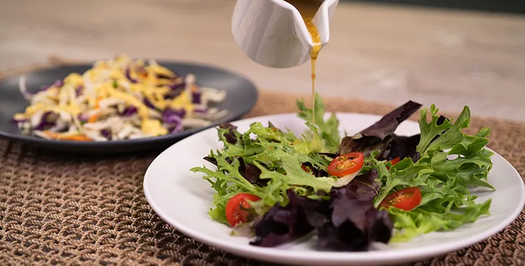 Salad in bowl with dressing being poured over it