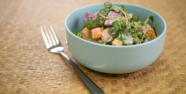 Kūmara and watercress salad with diced cooked sweet potato, fresh watercress, and a creamy mayo‑yogurt dressing, served in a light blue bowl.