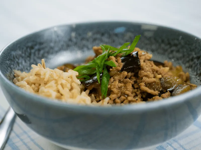 Mapo eggplant with pork—spicy minced pork and tender eggplant in a savory chili‑bean sauce—served over rice and topped with sliced scallions.