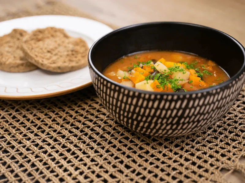 Hearty minestrone soup with diced vegetables, beans, and pasta in a tomato‑herb broth, served with whole‑grain bread on the side.