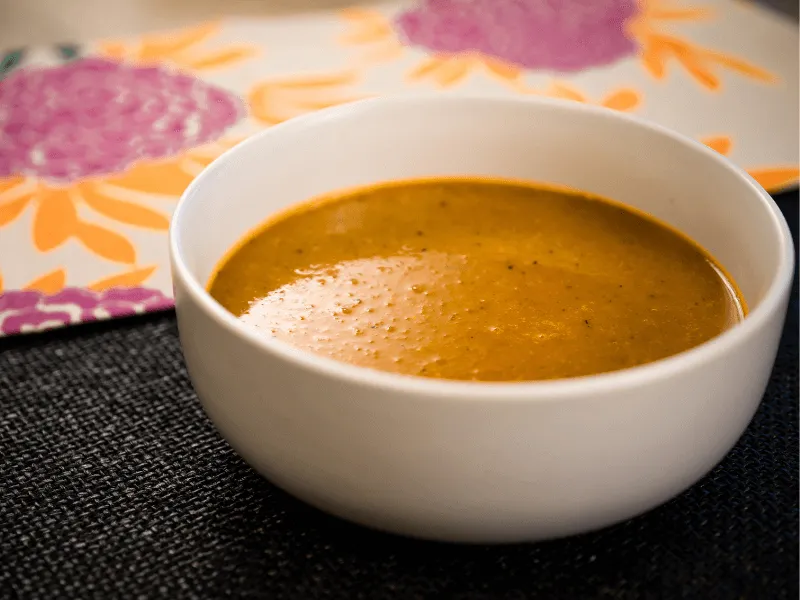 Smooth Moroccan roast pumpkin soup, blended with warm spices like cumin, coriander, and cinnamon, served in a white bowl.