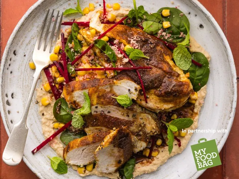 Moroccan-spiced chicken with veggie couscous and hummus plated with beetroot, corn and spinach, Heart Foundation healthy lunch or dinner recipe in partnership with My Food Bag.