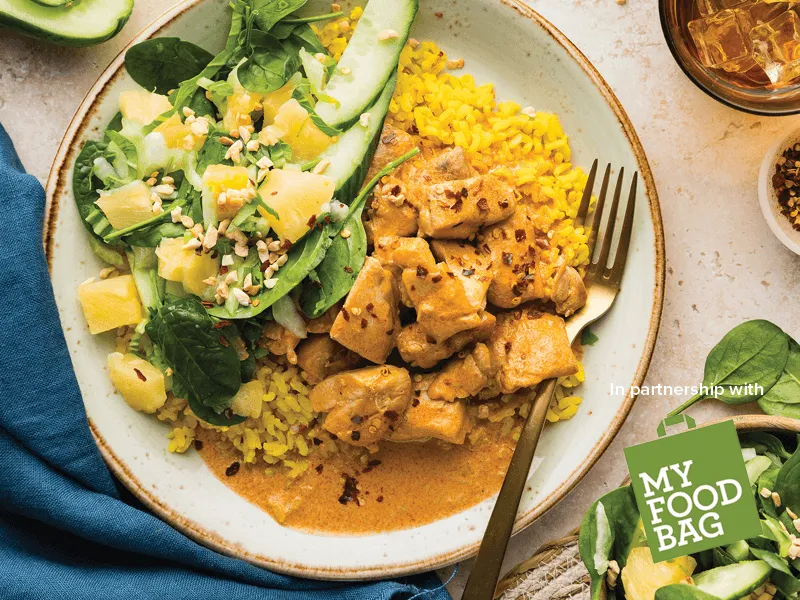 Bowl of chicken rendang curry with sides
