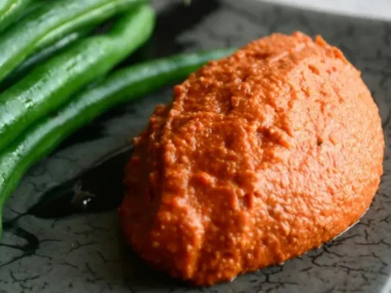 Smoky roasted capsicum dip spooned onto a plate beside steamed green beans.