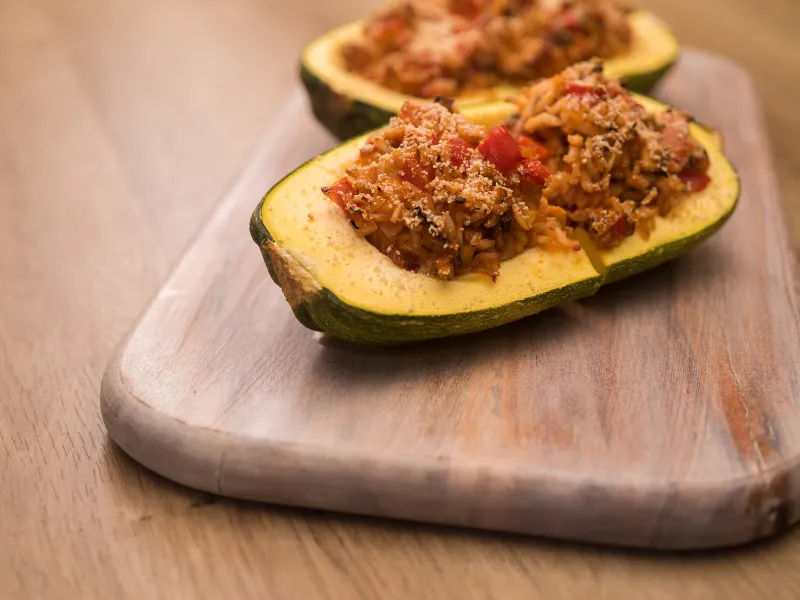 Baked stuffed kamo kamo with savoury rice and vegetable filling served on a board.