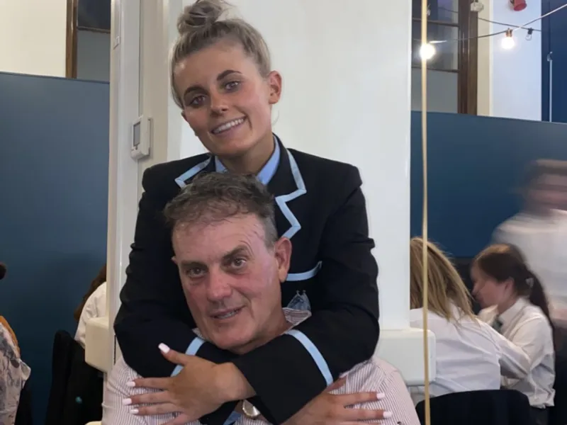 School student hugging parent at classroom event, celebrating family support and education together in New Zealand.