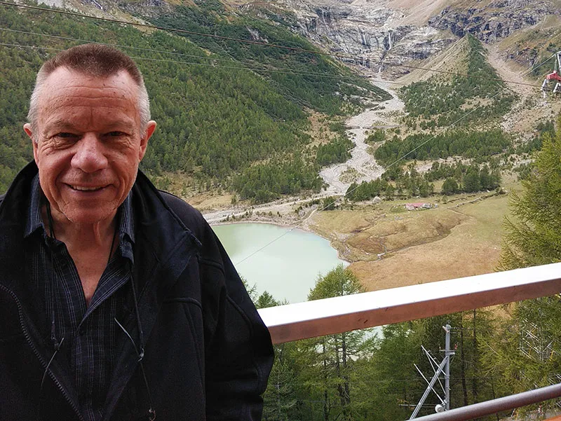 Doug stands with a view of a mountain valley behind him.