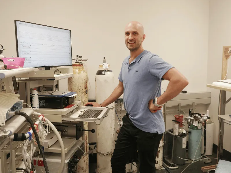 Dr Ryan Sixtus beside laboratory equipment used to investigate nerve activity and high blood pressure after aortic dissection.