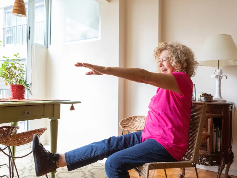 Older adult doing chair exercises at home to stay active and improve heart health.