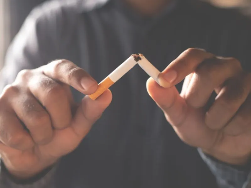 Close-up of a person breaking a cigarette in half with both hands, symbolizing quitting smoking.