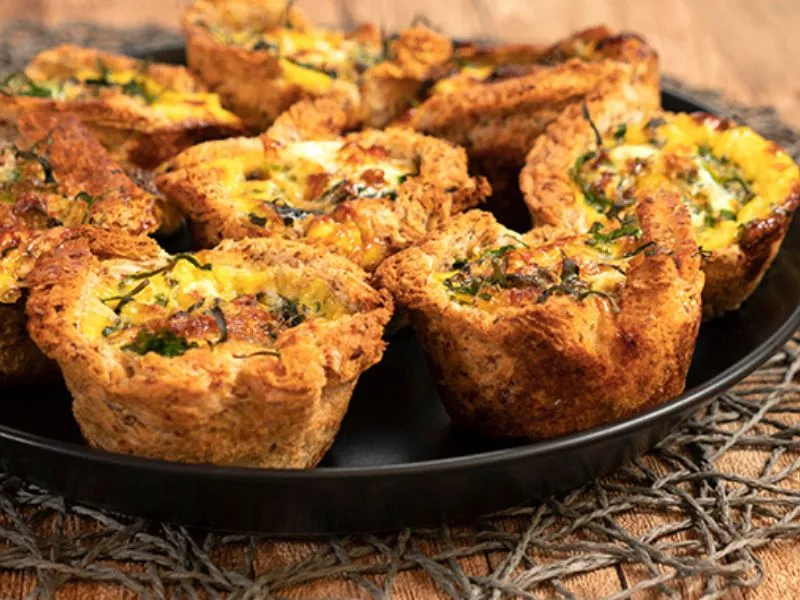 Spinach and cheese bread cases baked in a muffin tray, filled with cheese and greens