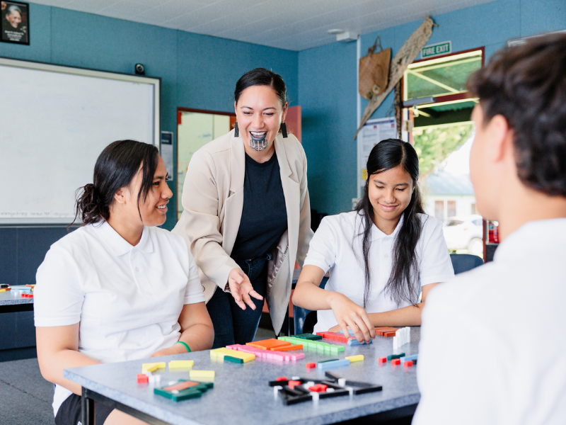 Three secondary students engaging with their teacher in class over an interactive activity.