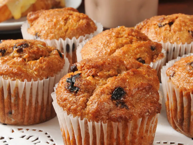 Homemade bran and raisin muffins in white paper liners, freshly baked and displayed on a doily for a healthy snack or school tuckshop treat.