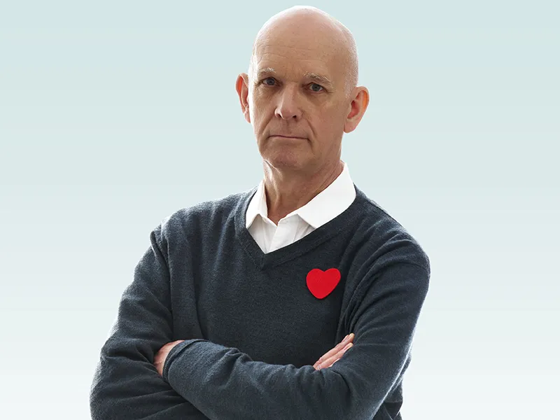 Middle aged man, Ian standing with his arms scrossed 