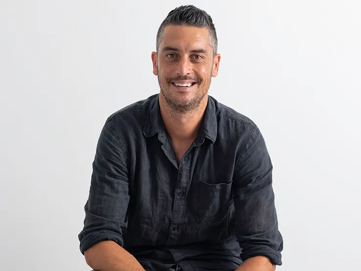 Duane is a youngish man (late thirties, early forties). he is wearing a blue shirt and is looking straight to camera, smiling.