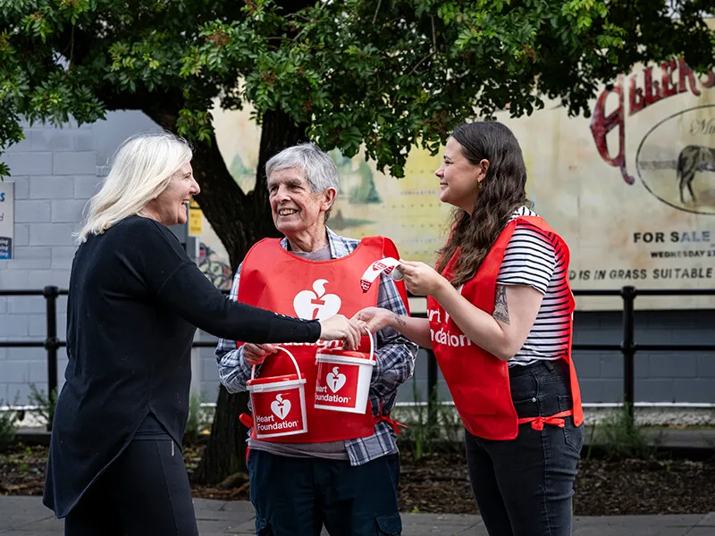 Two women with donation buckets together out on the street talking to the public about heart health and support for the heart foundation.