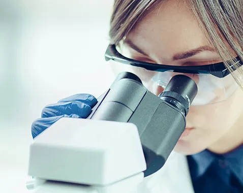 Researcher looking into a microscope