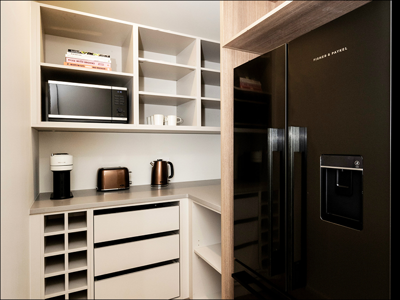Modern butler’s pantry with built-in shelving, black Fisher & Paykel fridge, and stainless steel appliances in a contemporary Wanaka home.