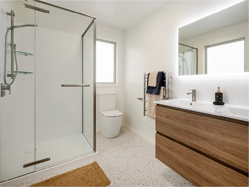 Luxury bathroom with walk-in glass shower, wooden vanity, and bright natural light.