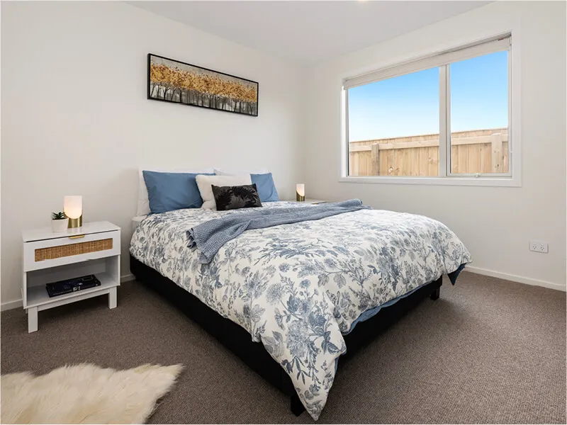 Stylish double bedroom featuring floral blue bedding, large window, and ambient lighting.