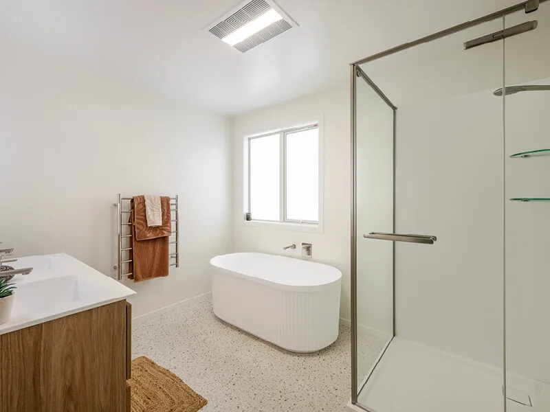 Spacious contemporary bathroom with freestanding bathtub, glass shower, and natural finishes.