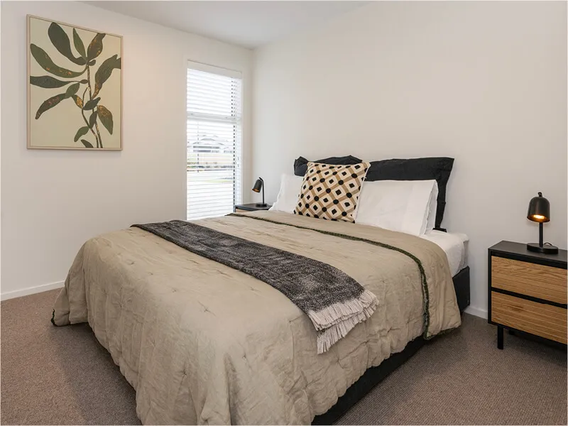 Light-filled bedroom with double bed, modern decor, and large windows in a newly built home.