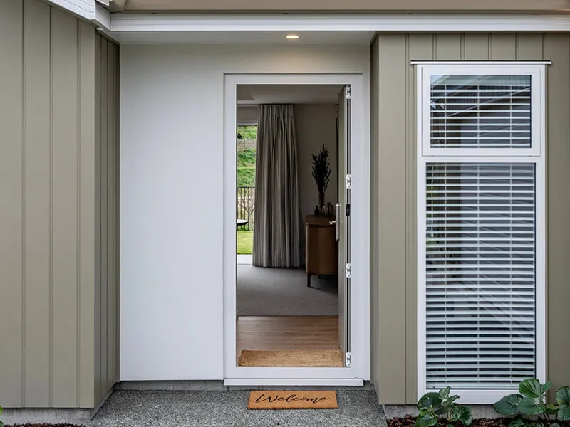 Welcoming front entrance of a modern home featuring a glass front door and a 'Welcome' doormat.