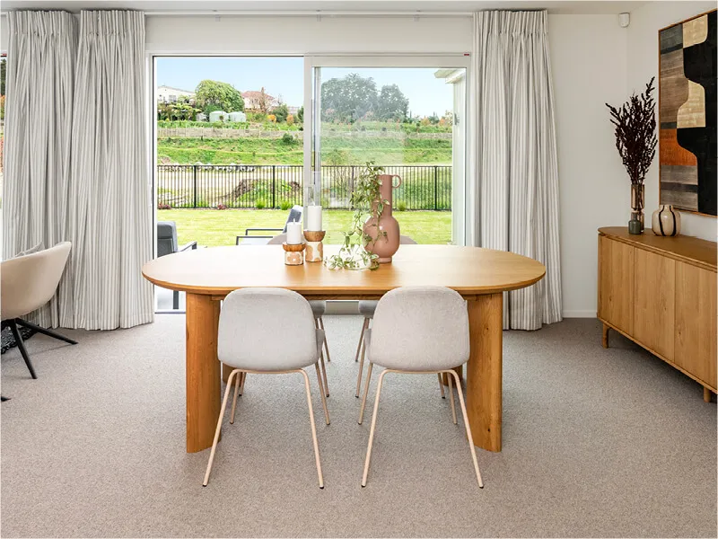 Dining room with large wooden table, modern chairs, and scenic outdoor views through sliding doors.