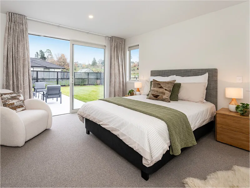 Modern master bedroom with access to a private patio, garden views, and soft, neutral furnishings.