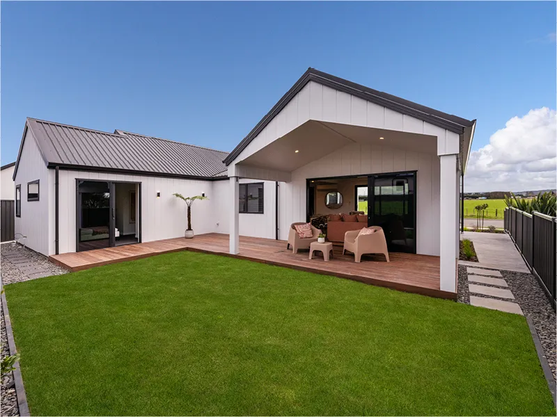 Covered outdoor living area of the Napier home showing gable-roof pavilion, timber deck, and outdoor lounge set overlooking green lawn.